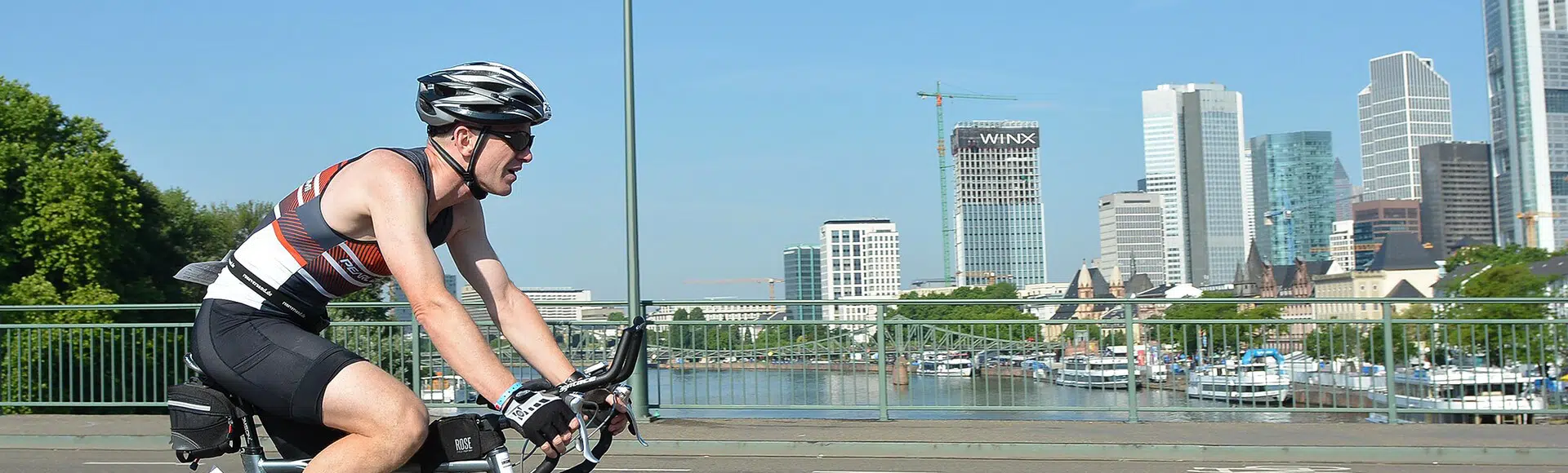 Mann in Sportkleidung fährt auf Rennrad über eine Brücke